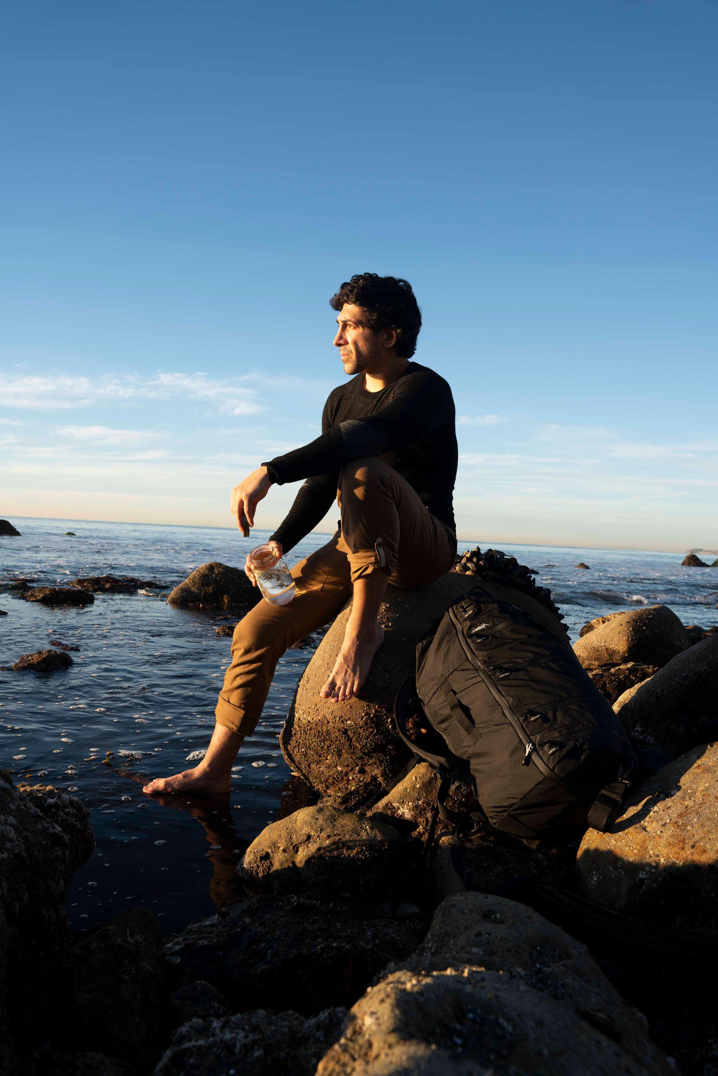 迈克尔·泽沃斯坐在太平洋海岸线上的一块岩石上