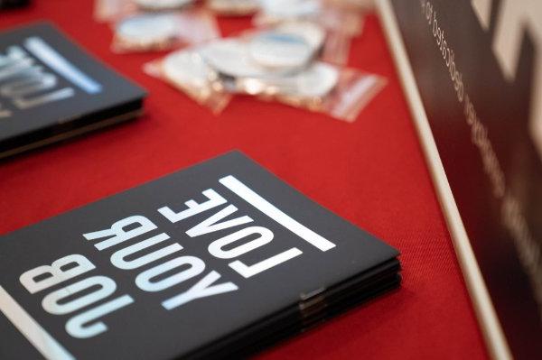 notebooks that read Love Your Job on a red tablecloth, pins in plastic near the top