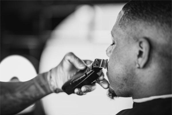 a barber trims the beard of a customer, black and white photo