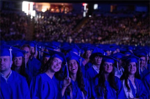  毕业典礼上，戴着蓝色帽子、身穿蓝色礼服的毕业生面带微笑.